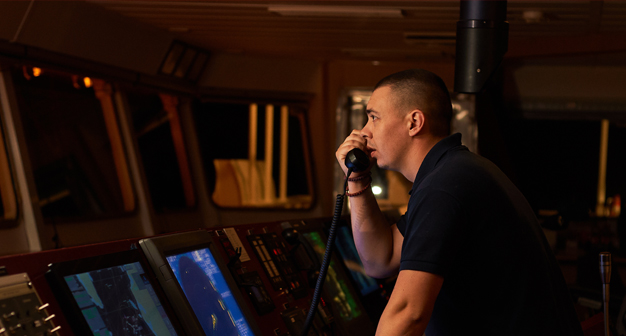 A person on the bridge of a ship using the phone. 